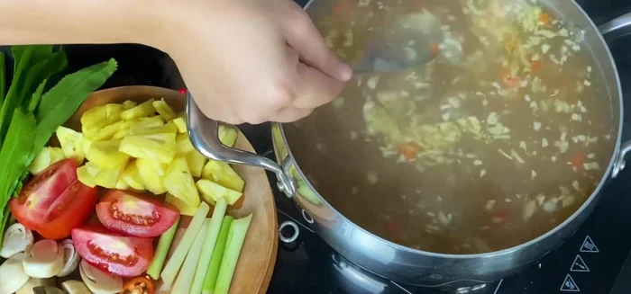 Thêm tương, sả (cắt khúc), thơm (cắt nhỏ), cà chua vào nồi nước dùng.