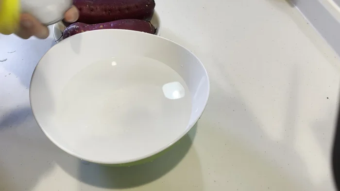 Chuẩn bị một thau nước, ngâm khoai lang vào để khoai không bị đen. (Nếu không thích hấp có thể luộc)