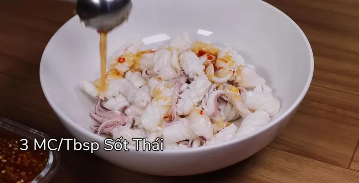 Cho mực vào tô lớn, trộn với 3 muỗng canh sốt Thái, ướp 10-15 phút.