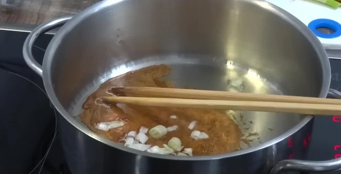 Cho hành tím vào nước màu, tiếp theo là tương ớt, đảo đều.