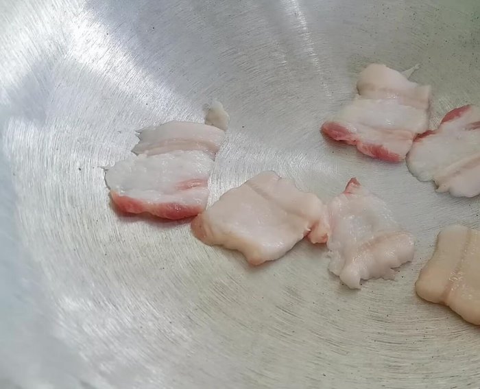Lót một lớp thịt ba chỉ mỏng xuống đáy nồi. Xếp cá đã ướp lên trên, xen kẽ với lá trà xanh, hành lá và thịt ba chỉ. (236.84)