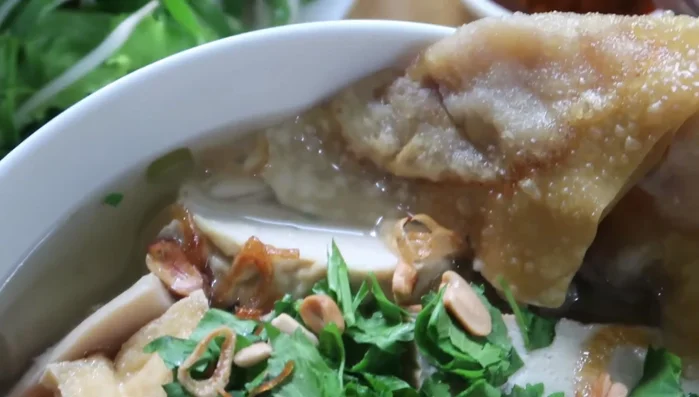 Tắt bếp, múc hủ tiếu chay ra tô, ăn kèm rau sống và bánh chưng.
