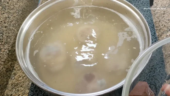 Khi nước sôi, hạ lửa nhỏ, nấu cho gạo nở.