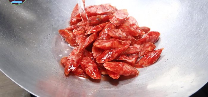 Cho lạp xưởng vào chảo, thêm 100ml nước, đun lửa trung bình cho đến khi nước hơi cạn và lạp xưởng bắt đầu săn lại (60.199)