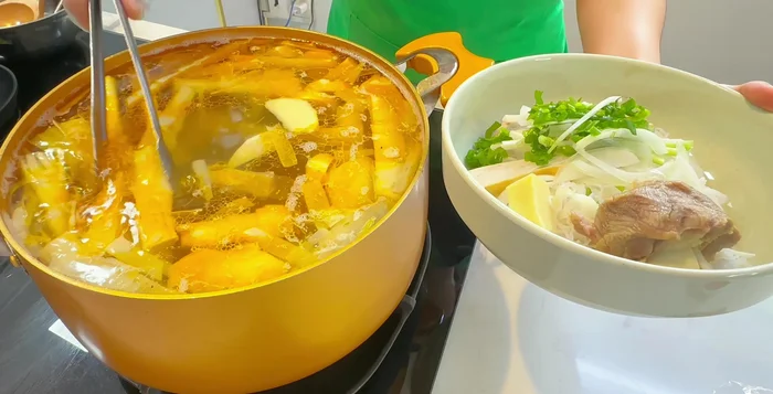 Cho xương hầm, măng vào tô, chan nước dùng nóng hổi.