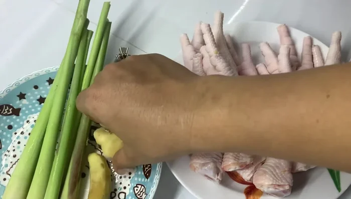 Luộc sơ chân gà với sả và gừng để khử mùi tanh và tạo mùi thơm.