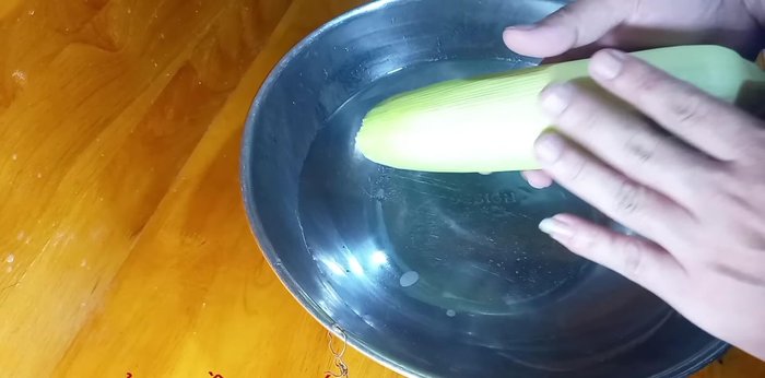 Rửa sạch bắp với nước, cho vào thau ngâm với 3 muỗng cà phê muối khoảng 10 phút để loại bỏ bụi bẩn, thuốc sâu (174.28-262.88)