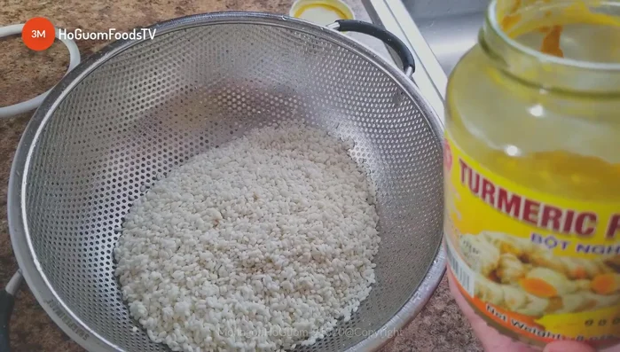 Cho gạo nếp (500g) vào nồi cơm điện. Thêm nửa lít nước, bột nghệ (1/3 thìa cà phê), và muối (1/3 thìa cà phê). Trộn đều.