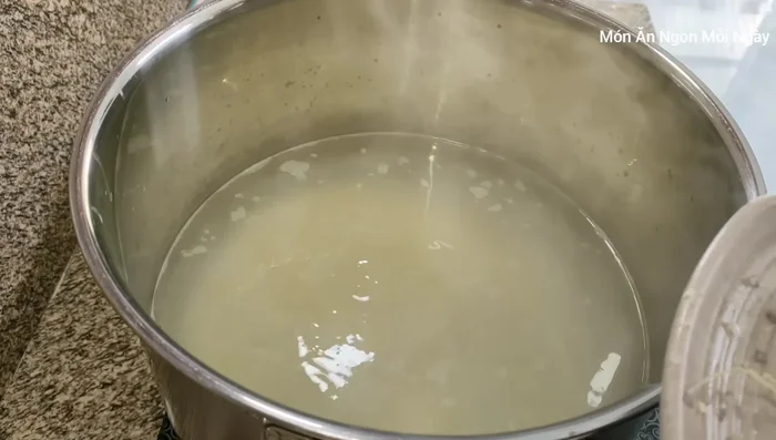 Thêm sả, hành tây, gừng vào nồi cháo.