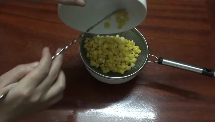 Sau khi ngâm, vớt ngô ra để ráo nước.