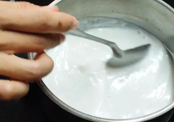 Từ từ cho bột sắn dây vào nước cốt dừa đang sôi, khuấy đều cho đến khi đạt độ sệt mong muốn.
