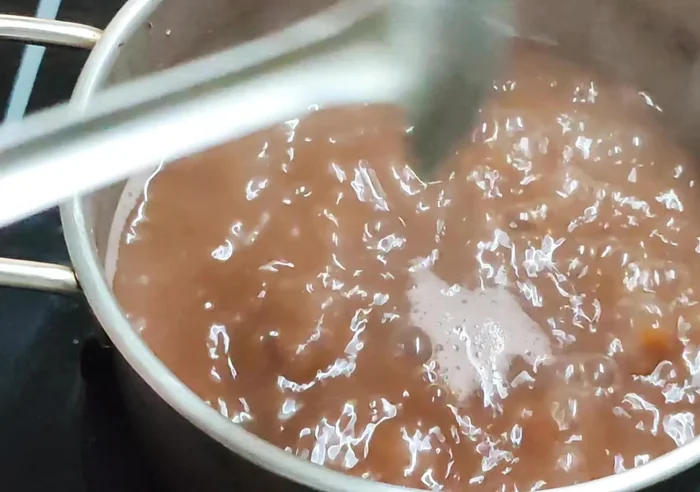 Khi đậu đỏ chín mềm (bóp vỡ), vớt ra, thêm 1/8 muỗng cà phê muối.