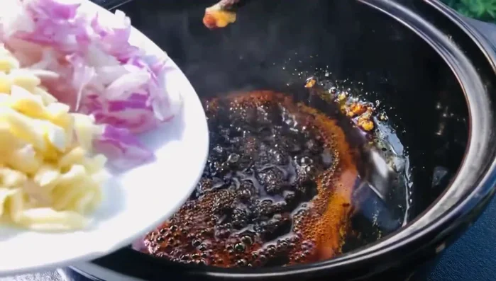 Cho hành, tỏi vào nồi nước màu, đảo nhẹ.