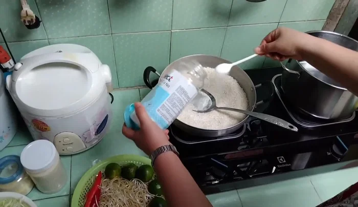 Rang gạo với 2 muỗng muối đến khi vàng đều. Lưu ý: Rang với lửa vừa để gạo không bị cháy.
