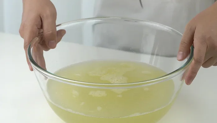 Lọc nước luộc gà để loại bỏ cặn.