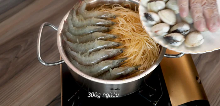 Cho tôm, mực, nghêu lên trên miến. Đè nhẹ hải sản xuống.