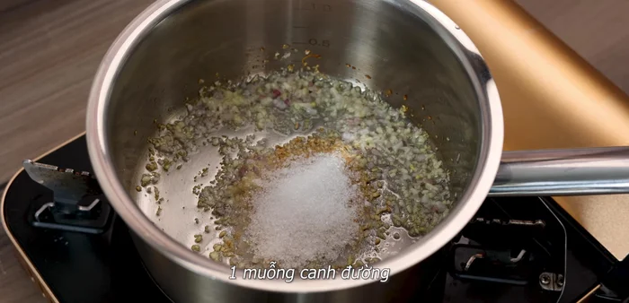 Cho mè rang, đường, nước mắm, dầu hào, nước tương, hạt nêm, bột ngọt, nước vào chảo, khuấy đều cho gia vị tan. Nêm nếm lại cho vừa ăn.
