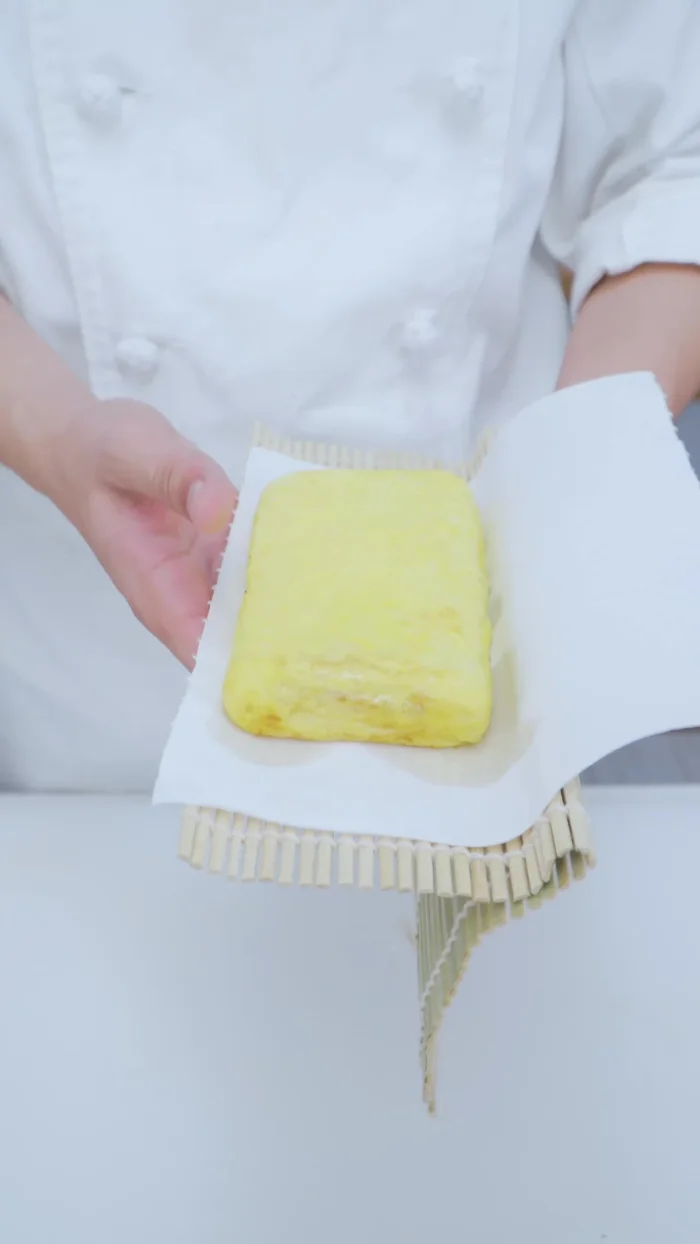 Đặt tamagoyaki lên khăn giấy/khăn vải khô, dùng dĩa đè lên khoảng 2-3 phút để tạo hình.