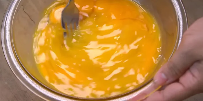 Đập trứng gà vào tô, đánh nhẹ tay cho đến khi lòng đỏ và lòng trắng hòa quyện, không tạo bọt khí (102.96).
