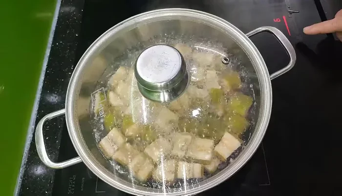 Chuối xanh gọt vỏ, ngâm nước muối loãng rồi rửa sạch. Luộc chuối cho đến khi không còn chát (61.079).