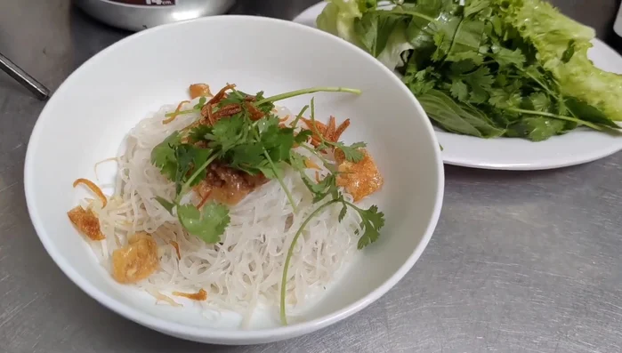 Cho bánh phở vào tô, thêm gia vị, hành phi, tóp mỡ, hành tươi.