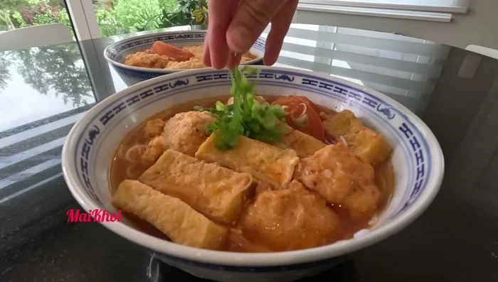 Múc bún ra tô, cho topping (đậu hũ, chả tôm, hành phi, tiêu, ớt, chanh) lên trên, chan nước dùng và thưởng thức.