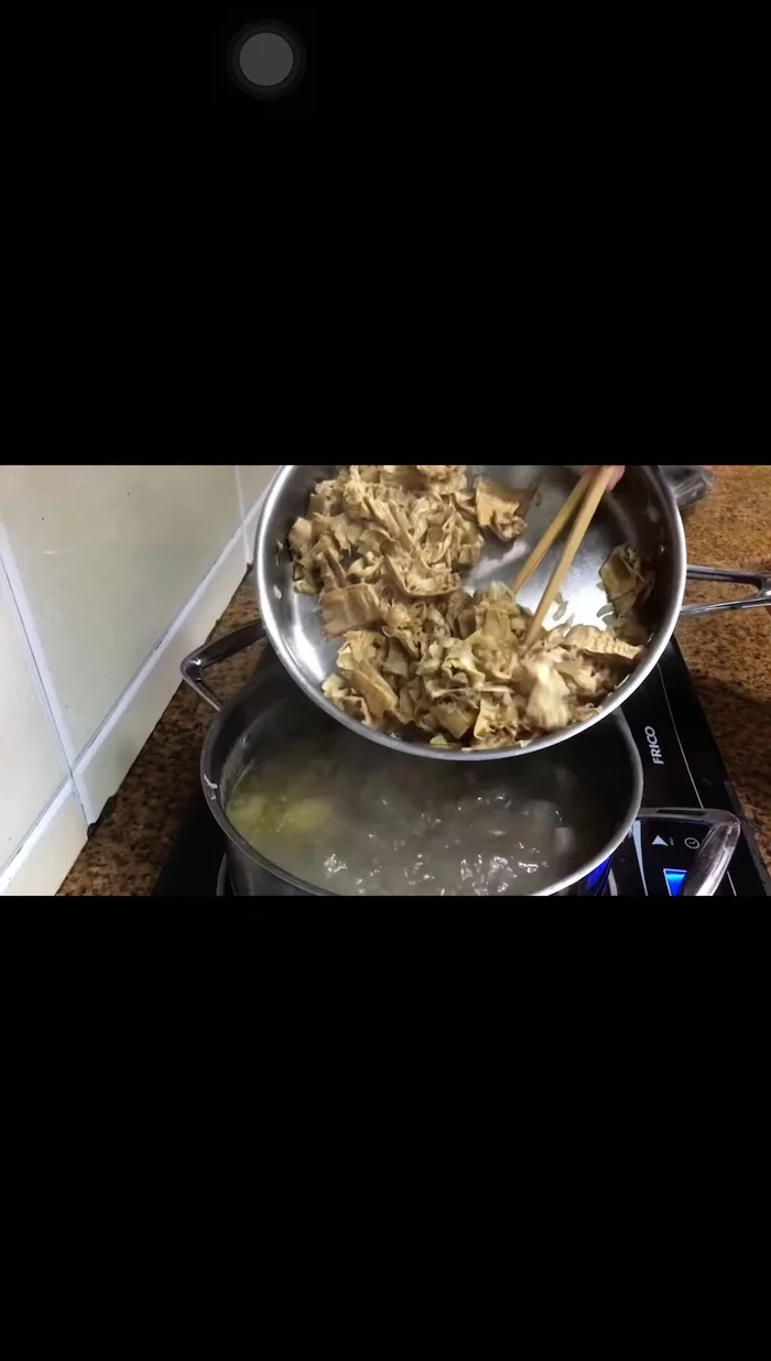 Cho măng khô đã xào vào nồi nước dùng.
