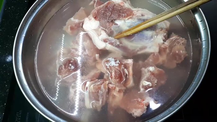 Trần xương với nước lạnh, thêm muối, luộc sơ qua để loại bỏ tạp chất và mùi hôi. (Nếu dùng thịt chân giò thì luộc cùng)