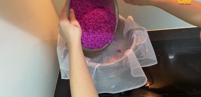Dùng khăn trải đáy xửng hấp để xôi không bị dính và ráo hơn. Khi nước sôi, cho nếp vào hấp 20 phút, xới đều và tạo lỗ trên bề mặt.