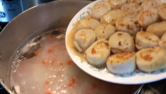 Cho sò điệp vào nồi cháo đang hầm.