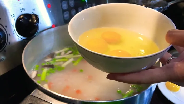 Đợi cháo sôi, cho trứng gà (3 lòng đỏ, 2 quả nguyên) và trứng bắc thảo vào.