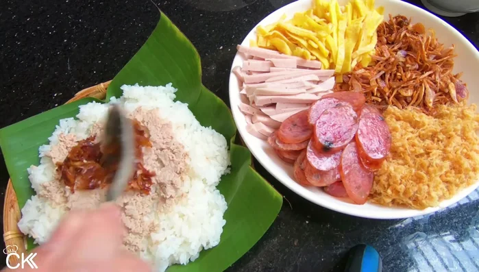 Múc xôi ra tô, xếp lần lượt các lớp topping: pate, ruốc, chả lụa, trứng, chà bông, hành phi.