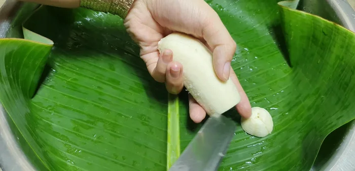 Lột vỏ chuối, cắt thành từng khúc dày, xếp vào nồi hấp lót lá chuối. (103.079)