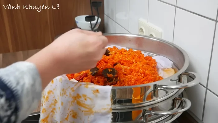 Cho đường vào nếp gấc đã hấp chín, trộn đều.