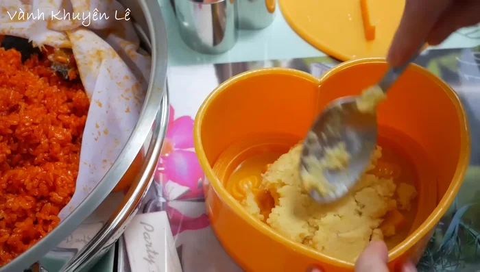 Cho đậu xanh vào khuôn, ép chặt. Cho nếp gấc lên trên, ép chặt.
