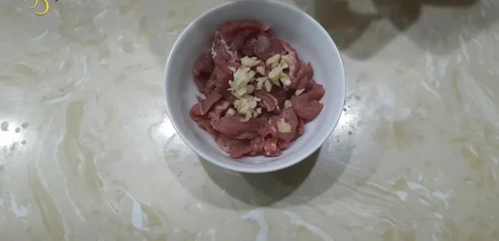 Ướp thịt bò với 1/2 thìa cà phê tỏi băm, 1 thìa cà phê hạt nêm, chút tiêu xay và 1 thìa cà phê dầu ăn trong khoảng 10 phút. (133.35)