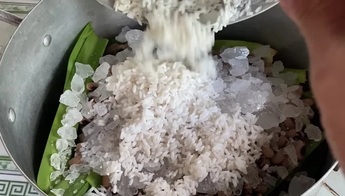 Cho nếp đã ngâm lên trên lớp đường, sau đó đổ 500ml nước lọc vào nhẹ nhàng.