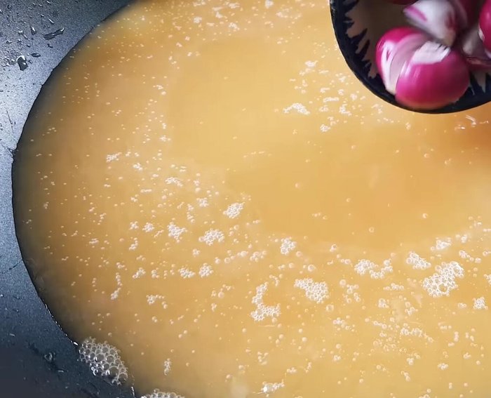 Phi thơm hành tím, tỏi và ớt khô trong chảo dầu nóng.