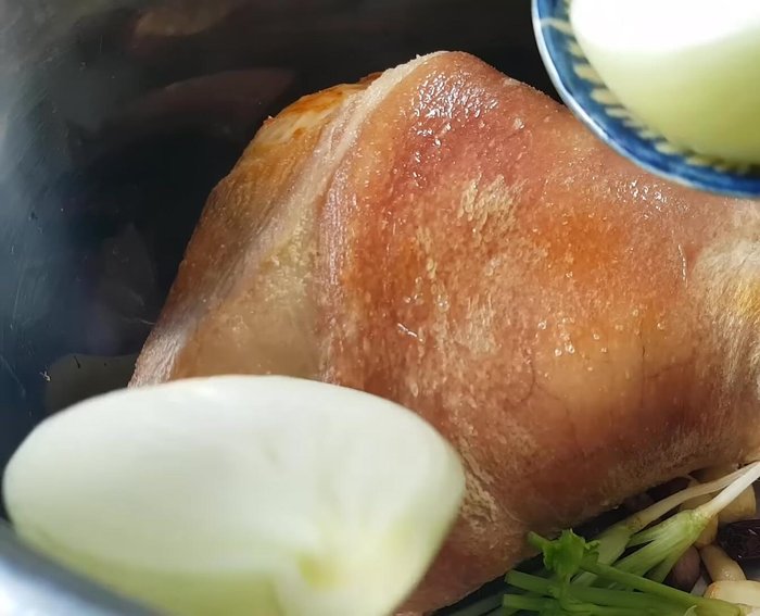 Cho chân giò chiên, hành tím phi, ngò rí, hành tây, nước lọc, nước dừa, nước tương, nước mắm, đường nâu, rượu trắng, hạt nêm và muối vào nồi lớn.