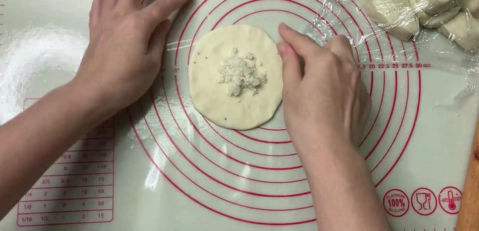 Cho nhân bánh vào giữa miếng bột, gấp lại và miết chặt mép để nhân không bị rơi ra.