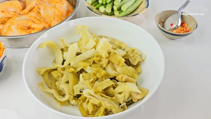 Trộn dưa cải chua với đường, tỏi ớt băm, nước mắm. Ướp ít nhất 1 tiếng.