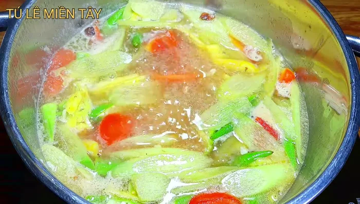 Cho cá vào: Cho cá hú đã luộc sơ vào nồi canh, đun sôi lại.