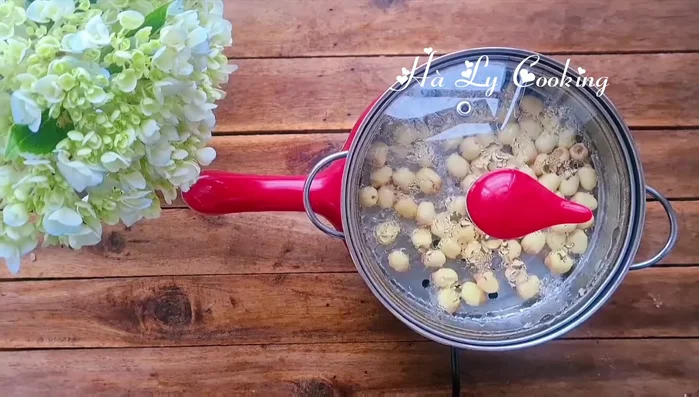 Hấp chín hạt sen cho đến khi mềm (khoảng 10 phút). Khi còn nóng, cho 1/2 lượng đường vào ướp.