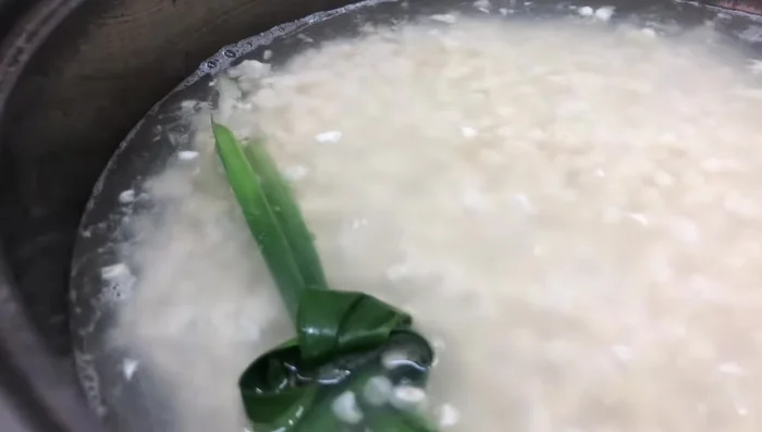 Cho đường, lá nếp vào nồi ngô đang đun.