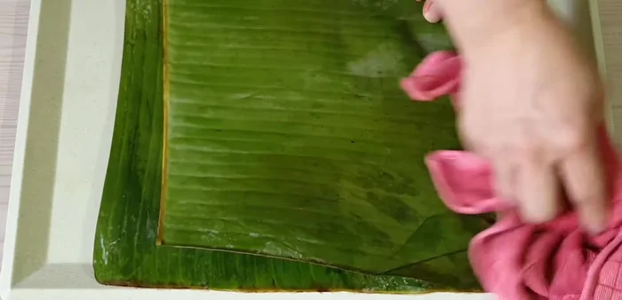 Gói bánh: trải lá chuối lớn, cho bột, nhân, trứng cút lên trên, gấp lá lại.