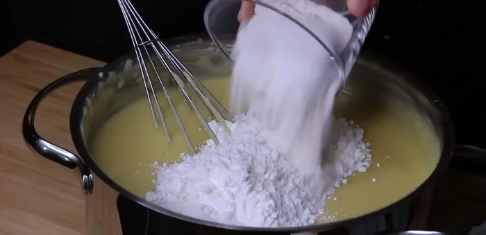 Cho 70g tinh bột bắp, 60g bột mì đa dụng, 2 lòng đỏ trứng gà, 1 muỗng cà phê tinh chất vani vào hỗn hợp, trộn đều đến khi không còn vón cục.