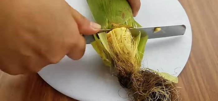Cắt bỏ đầu, đuôi bắp ngô, bóc bỏ lớp vỏ già, giữ lại lớp bẹ non và râu ngô. Rửa sạch và cắt đôi bắp ngô, chẻ dọc và tách riêng hạt ngô.