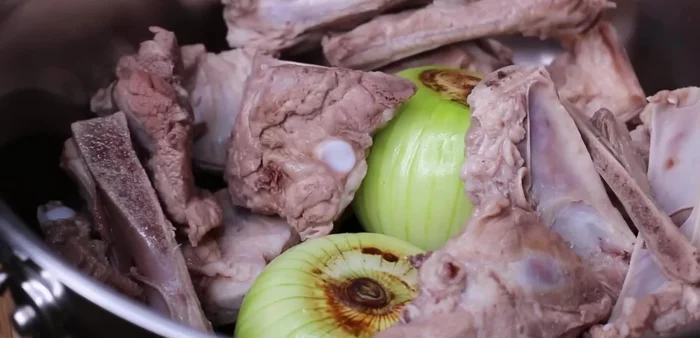 Hầm xương: Cho xương heo đã sơ chế, 2 củ hành tây nướng vào nồi, thêm 2.5 lít nước, 2 muỗng cà phê muối. Đun sôi, hớt bọt, đậy nắp, hầm nhỏ lửa 90 phút (hoặc 60 phút nếu thích xương không quá mềm).