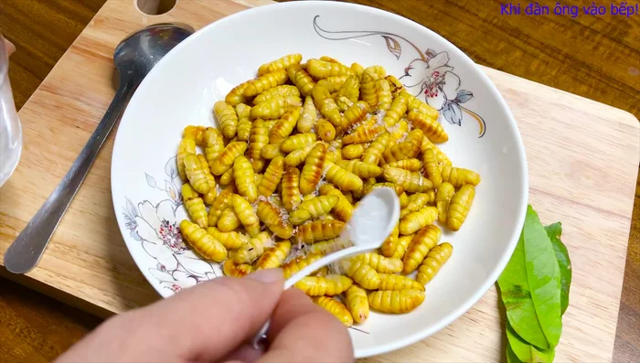 Ướp nhộng tằm với mì chính, đường, hạt nêm, tiêu. Trộn đều và để khoảng 20 phút. (61.55)