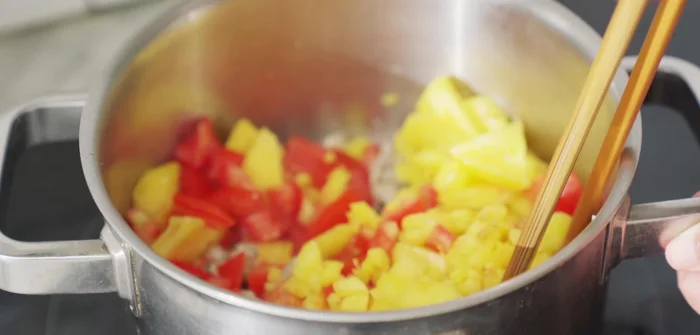 Cho cà chua hạt lựu và dứa hạt lựu vào xào cùng. Thêm 1 thìa cà phê bột nêm (hoặc bột canh) để cà chua nhanh mềm.